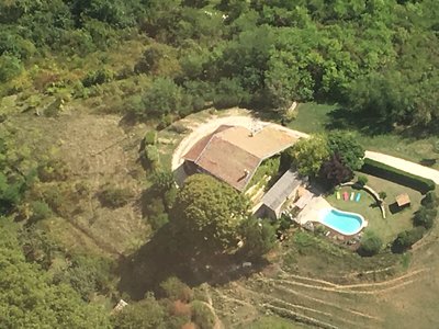 Vue de haut de la piscine et du gîte de Fontepaisse entourées de forêt prise d'un avion