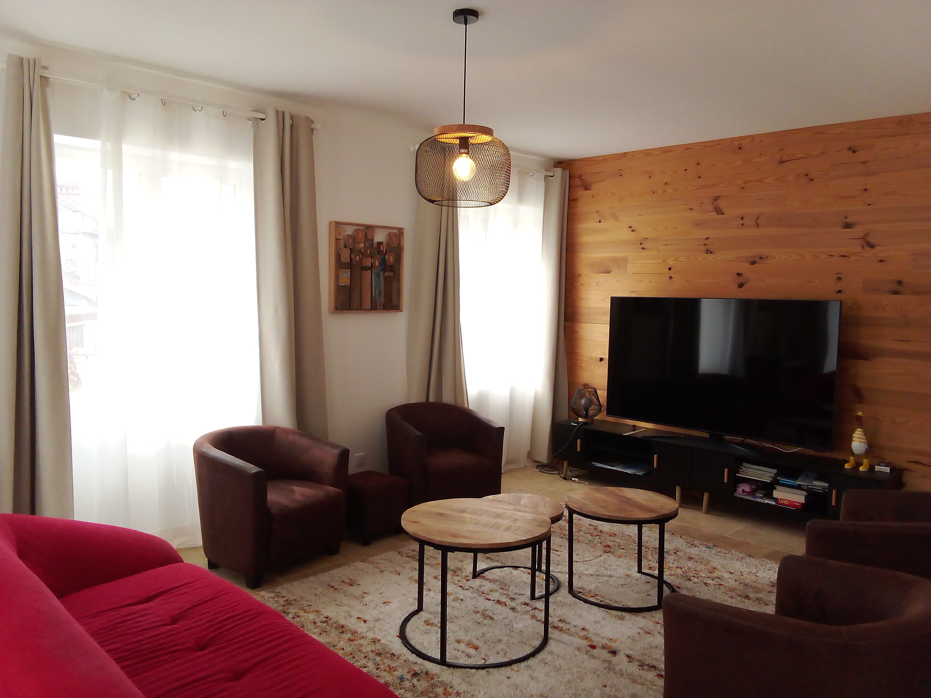Grand séjour lumineux avec canapé, fauteuil et écran plat.