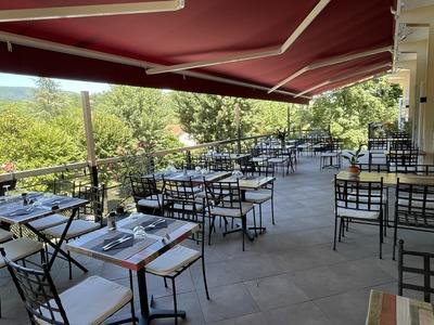 Terrasse conviviale, protégée du soleil par un large store, où une dizaine de tables sont installées, offrant une vue sur [...]